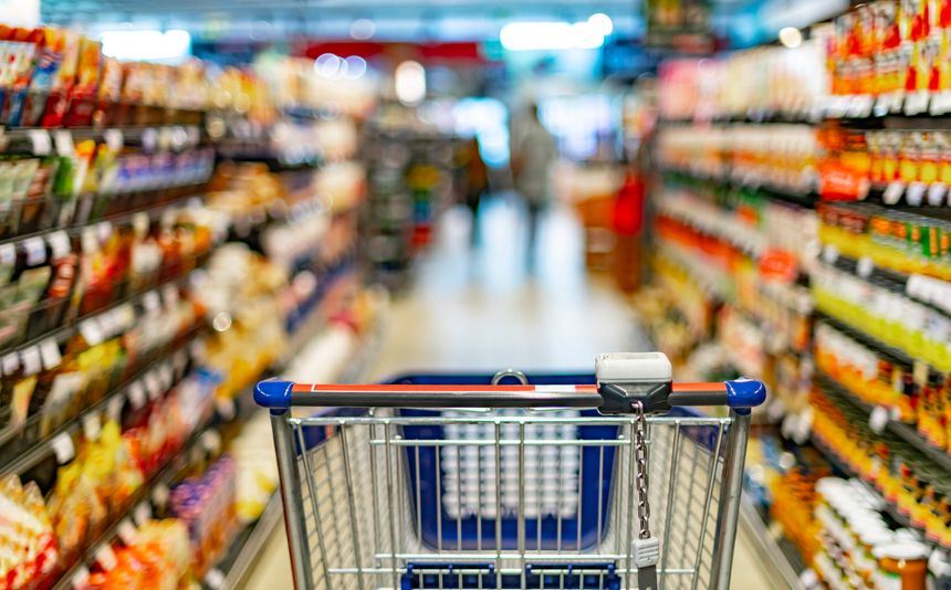 A shopping cart by a store shelf in a supermarket