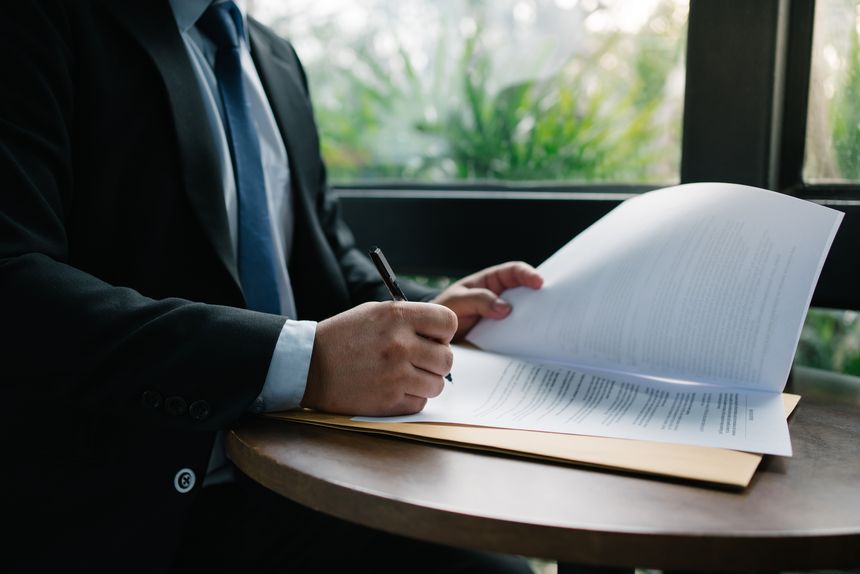 Businessman signing a document on a round table, showcasing legal agreement and professional commitment. Perfect for business, contract, and legal concepts.