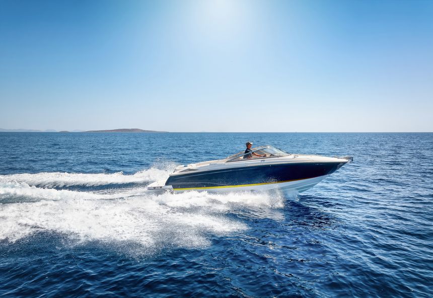 Side view of a motorboat cruising with high speed over the ocean and leaving a trail of bubbles and waves