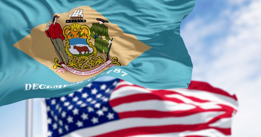 Close-up of Delaware state flag waving with the national american flag. Yellowish-beige rhombus shape with the state coat of arms on a pale blue background. 3d illustration render. Selective focus