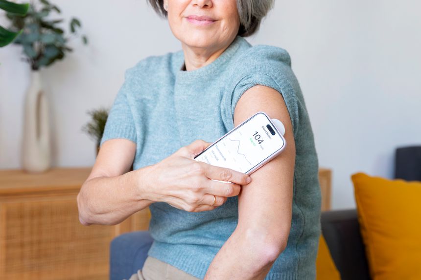 Adult woman tracking blood sugar levels using a continuous glucose monitor and smartphone at home