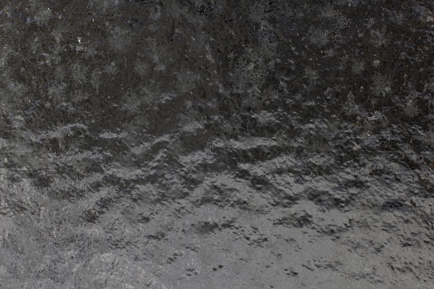 Frozen glass with intricate frost patterns and crystalline textures creating a cold, abstract winter background — detailed icy layers, matte shimmer, and stark natural structure..