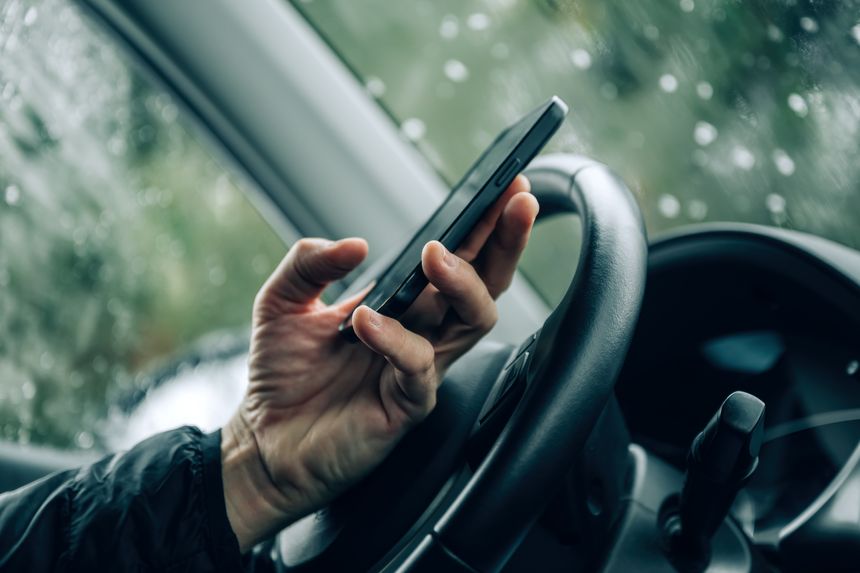 Concerned worried male driver using mobile phone in car on a cold winter day, selective focus