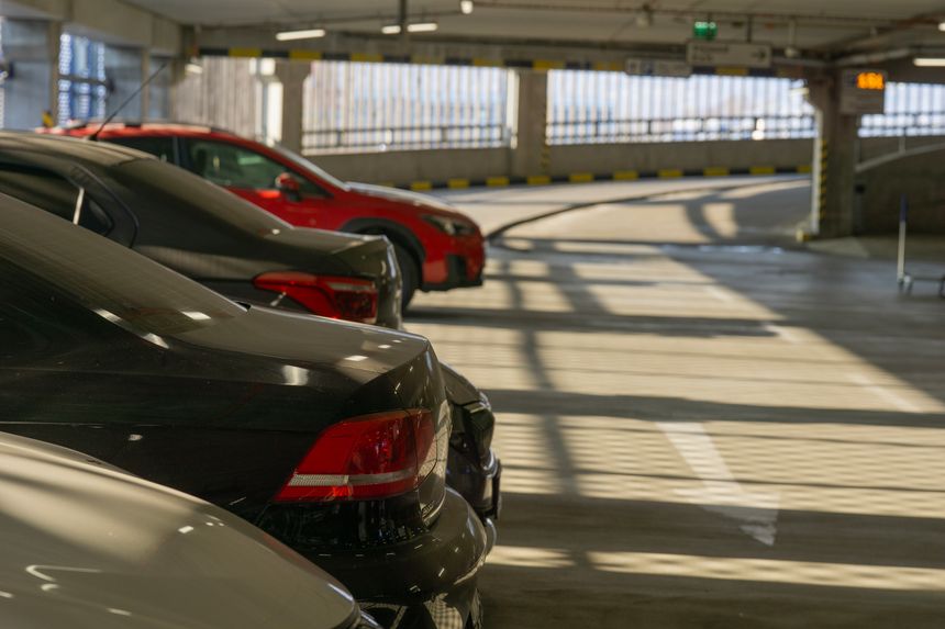 Multiple cars parked in a covered parking garage with sunlight casting shadows, representing urban transport, parking availability, and city infrastructure.