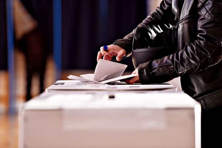 Hands holding a stamp casting a vote into the ballot box during elections