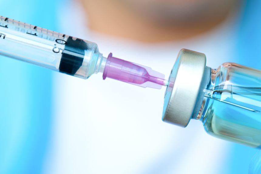 doctor's hand holds a syringe and a blue vaccine bottle at the hospital. Health and medical concepts.