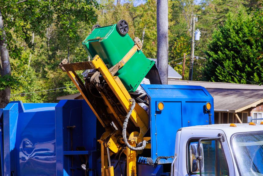 An employee of municipal cleaning service loads mixed domestic waste onto garbage truck for removal