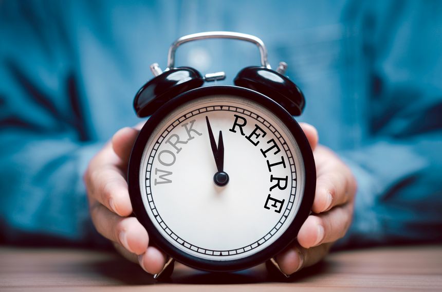 Businessman holding black alarm clock with clockwise countdown from work to retirement.