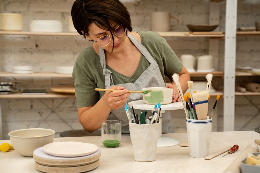 Painting ceramic products using acrylic paint and brush. Making a colorful decoration of a clay project with paint and water