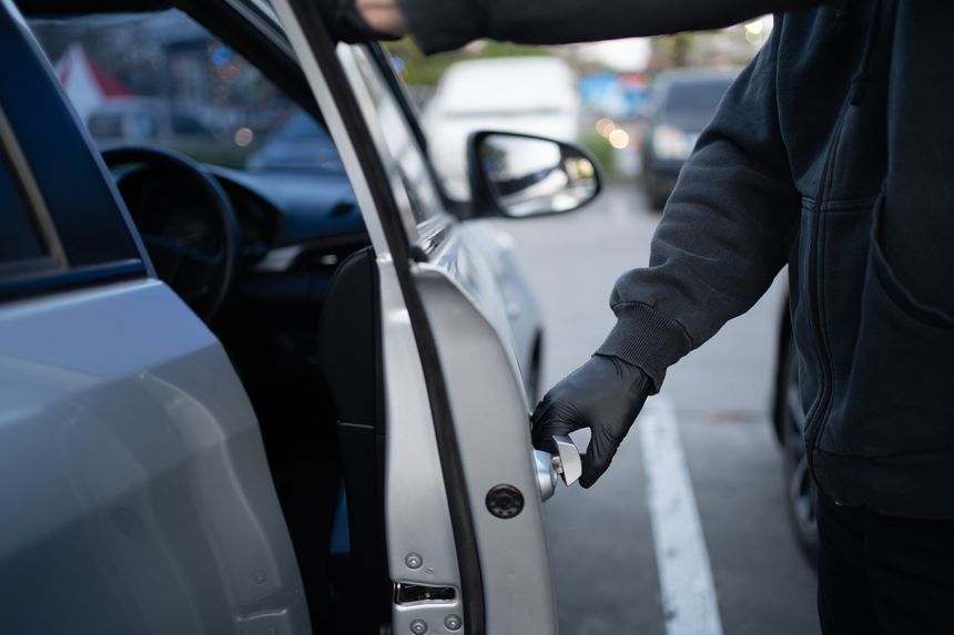 Close-up shot of a thief wearing a black shirt and black gloves. He tried to open the car door and tried to break in. car theft concept.