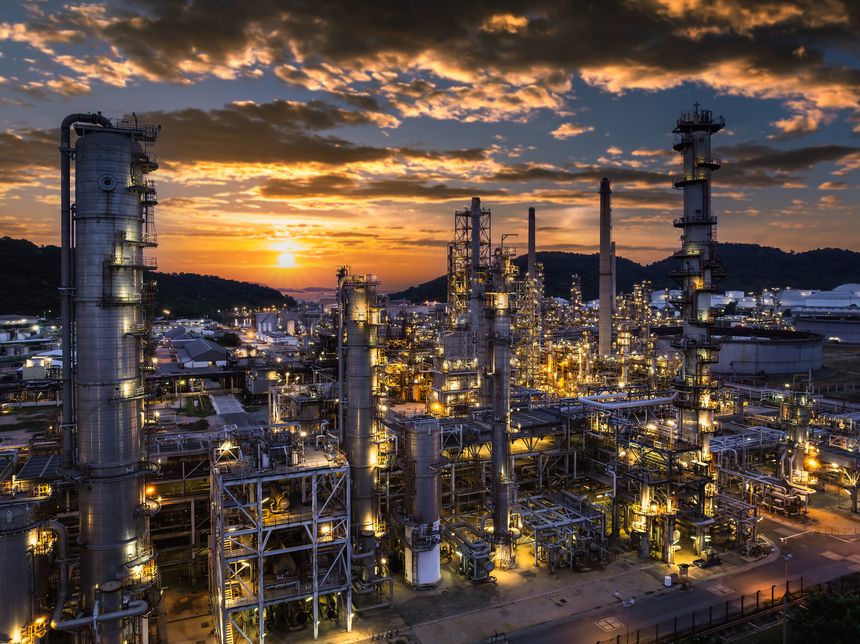 Oil refinery plant industry factory zone, oil and gas petrochemical industrial, oil storage tank and pipeline steel, twilight scene and over lighting equipment and the sunset and cloud sky background, aerial view