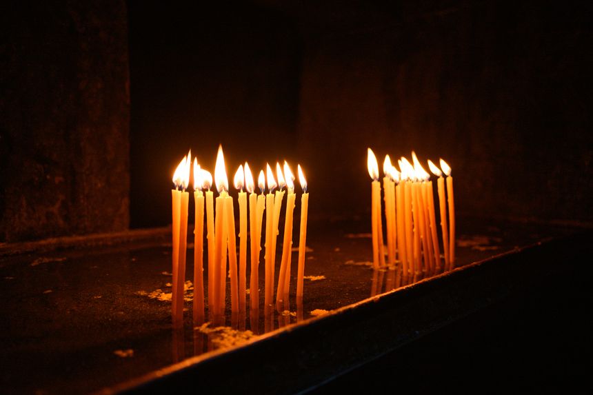 Lit candles in dark church interior, prayer and spirituality concept