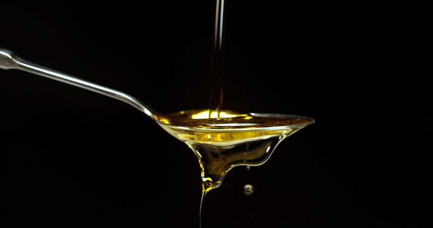 Olive Oil, Falling in a Spoon against Black Background