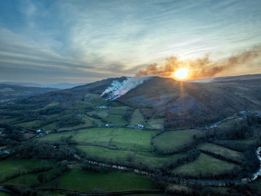 A grass fire at sunset on a hillside in the Brecon Beacons in South Wales GB