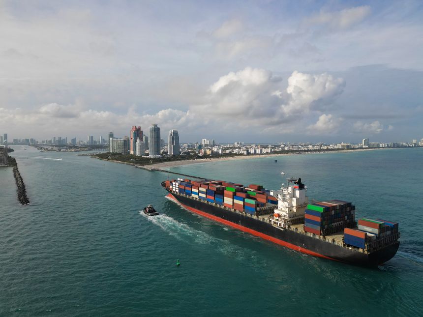 Freight container on cargo vessel. Cargo ship vessel leaving port. Container ship. Export and import. Cargo business. Port of Miami. Ship with container, aerial view. Cargo shipyard activities.