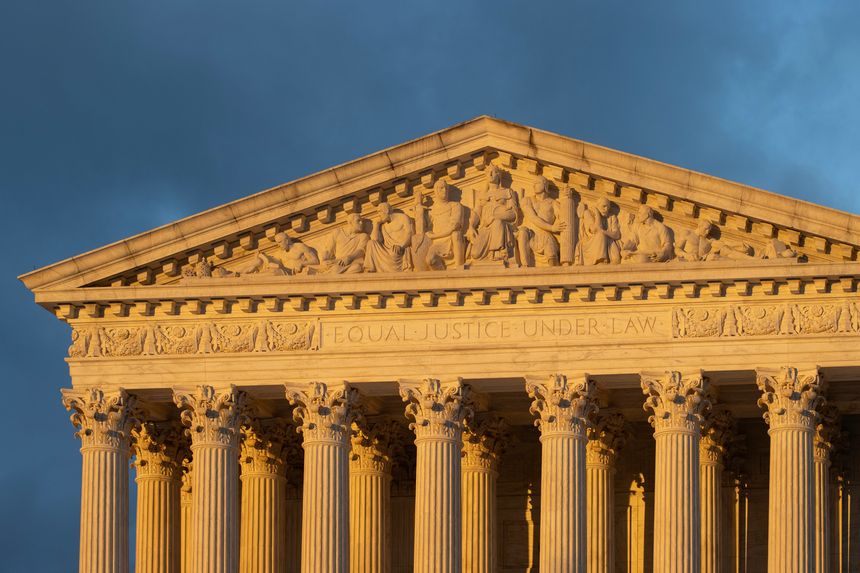 Front view of the Supreme Court Building in Washington, DC, against a dramatic stormy sky during sunset.