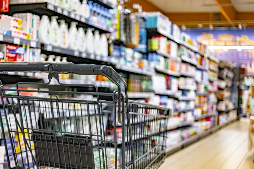 A shopping cart by a store shelf in a supermarket