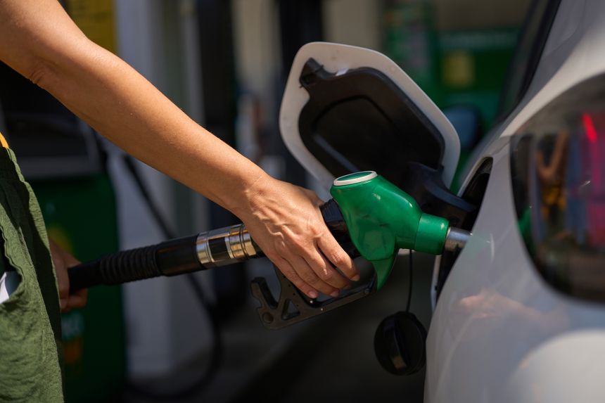 Close up of a woman's hand holding a gas pump, refueling her car at a gas station