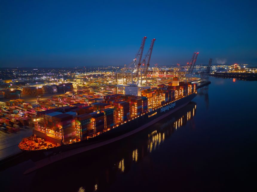 Aerial view of Hapag-Lloyd container ship at Southampton Docks UK. Beautiful industrial and city lights with reflection. Illuminated container terminal at night. Southampton, UK, 12.05.2023