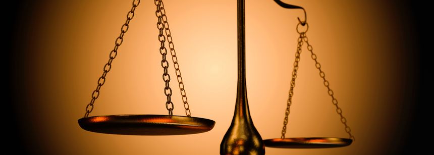 A close-up shot of antique brass scales of justice, illuminated by warm light, representing legal fairness and equilibrium