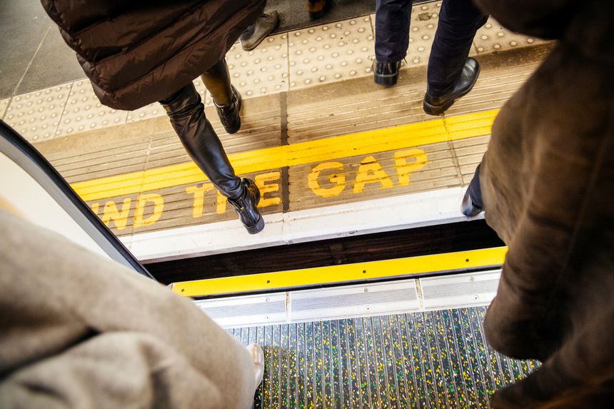 London: Directly above view at Mind the gap sign in London Underground metro train station with feets of pedestrians exiting entering metro train