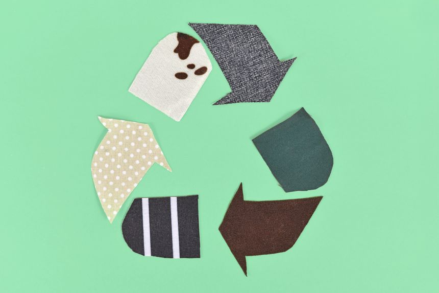 Recycling arrow symbol made from old textile pieces on green background