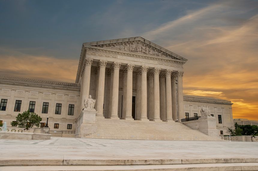 Marble architecture of American Supreme Court with sunset in the background.