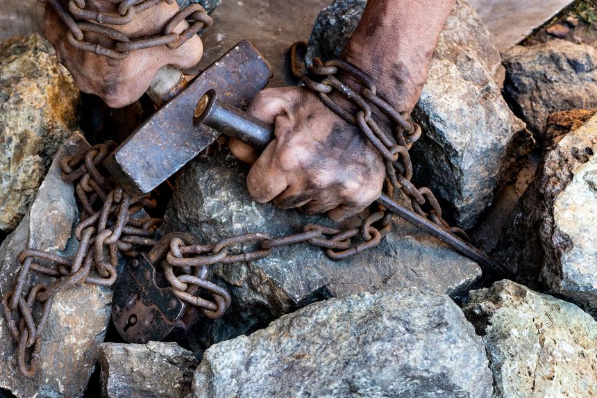 The hands of a slave in an attempt to release. The symbol of slave labor. Hands in chains.