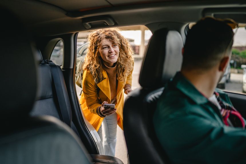 A young curly hair woman get into a taxi with a suitcase
