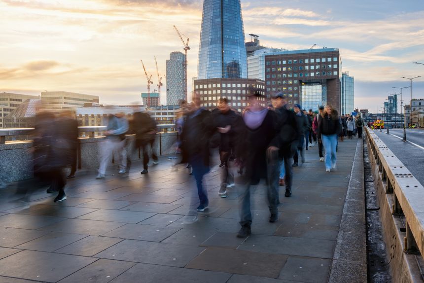 Blurred motion view of business people rushing into their offices in the City of London, England, during early morning sunrise