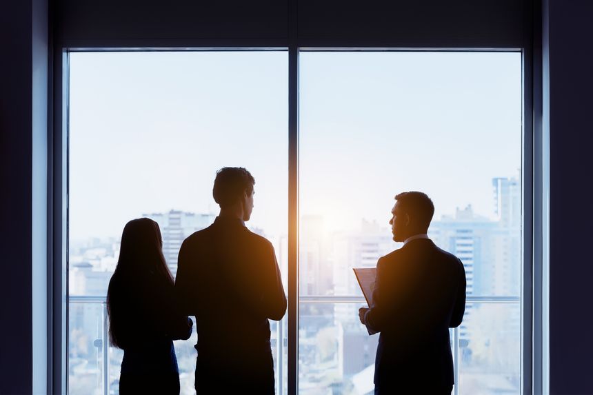 Couple and real estate agent stands near window and speaks before signing contract. Business concept