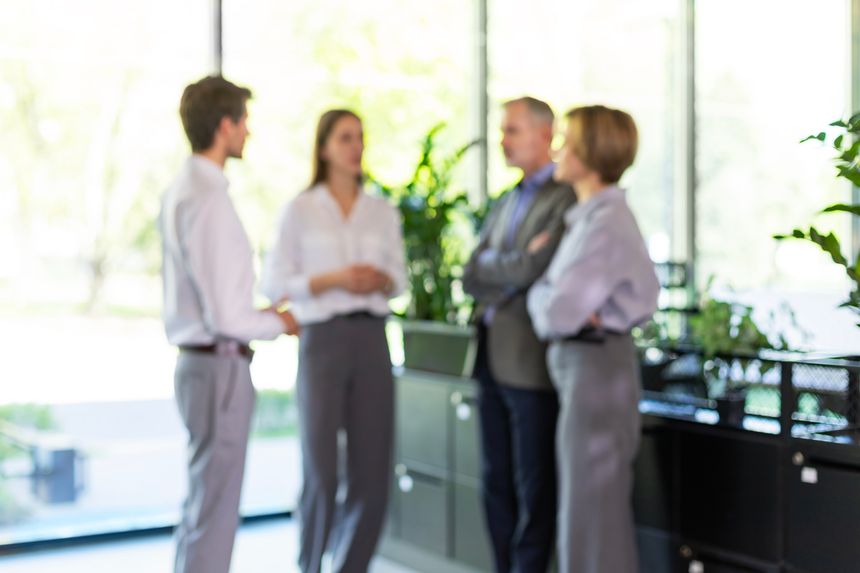 Group of business people standing together and discussing their work and projects, having a team meeting in an office