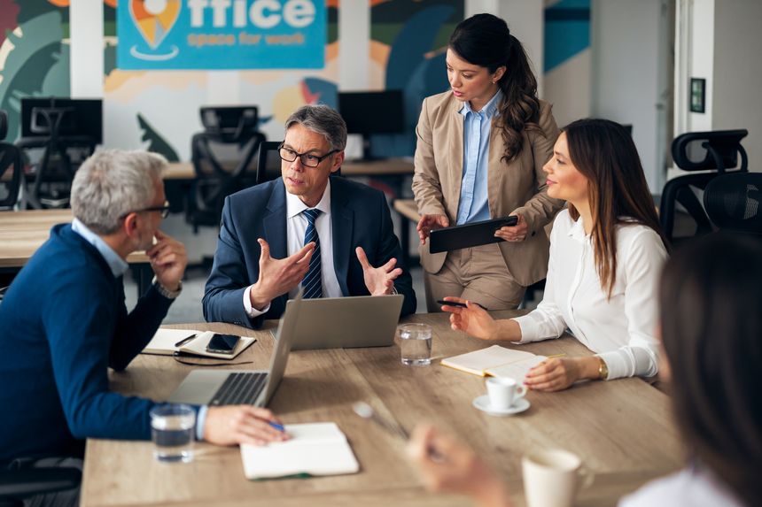 Group of business professionals collaborating during a meeting, discussing ideas, and working together in a modern office. Showcasing teamwork, communication, and professional engagement in a dynamic workspace environment.