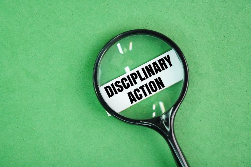 Magnifying glass and white paper with the word disciplinary action. a formal process used by employers to address an employee's misconduct, violation of company rules, or failure to meet performance