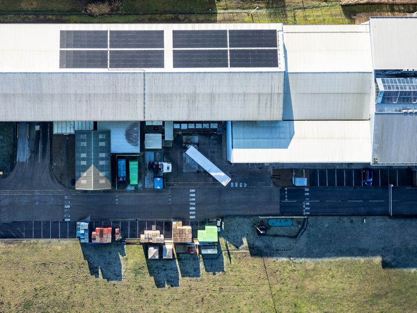 Drone top down view of a typical warehouse and transport facility in the UK. Note the stacked pallets and HGV trailers on the tarmac.