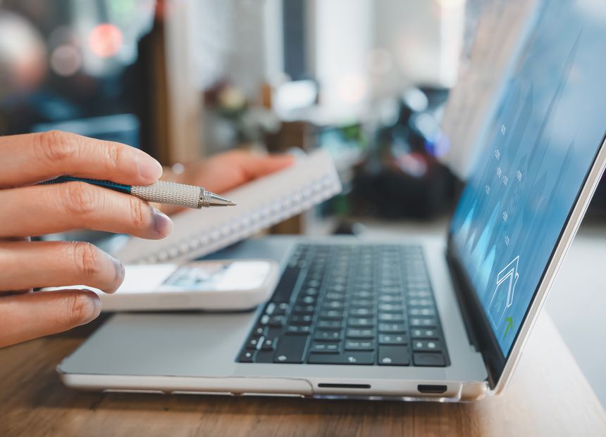 Business growth and real estate investment analysis concept.Hand holding pen pointing to financial charts on laptop,Businesswoman calculating financial data for long term investments, property market