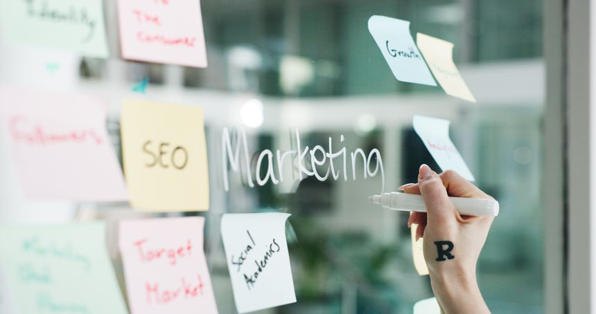 Advertising, hands writing or sticky note on glass wall for branding, seo plan or target audience trends. Digital marketing, awareness strategy or person at board for campaign project, ideas or goal