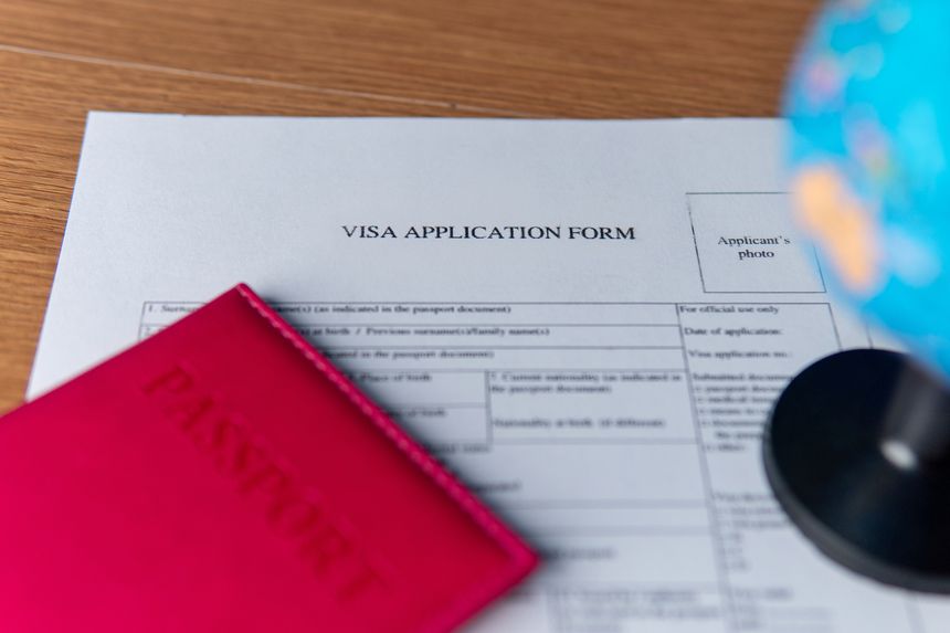 A visa application form, a red passport, and a globe. International travel concept.