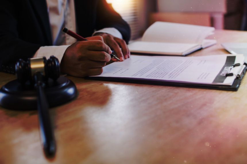hand of business people sign contract with justice hummer on table