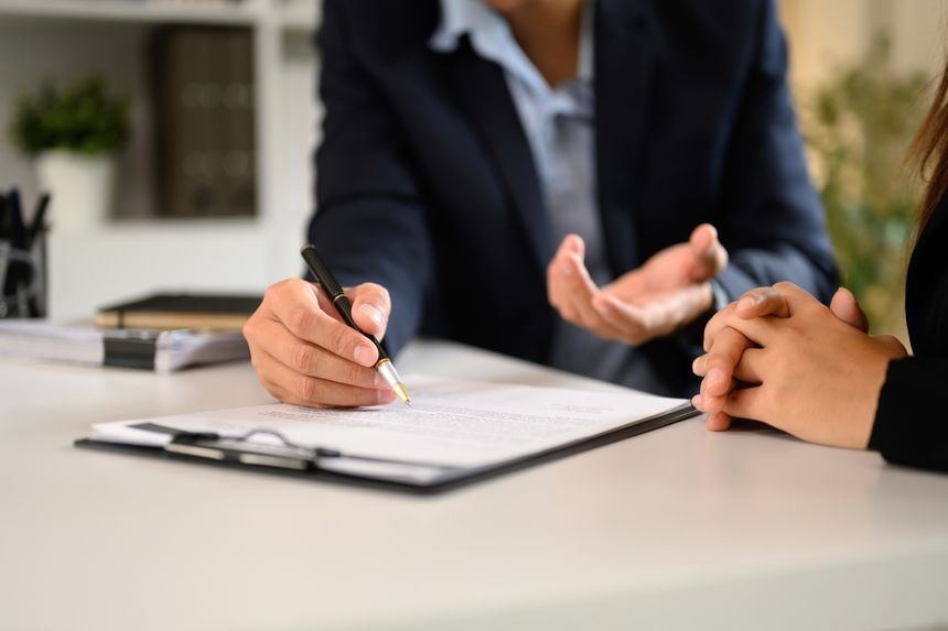 Two businesspeople in suits finalizing an important business deal at a modern office desk.