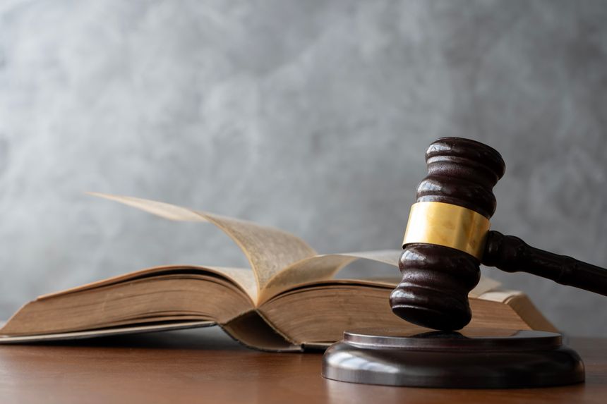 Court gavel placed near an open legal book with pages in motion, conveying justice, law study, legal authority, verdicts, and judicial decision concepts. Judge Gavel Beside Open Law Book With Turning.
