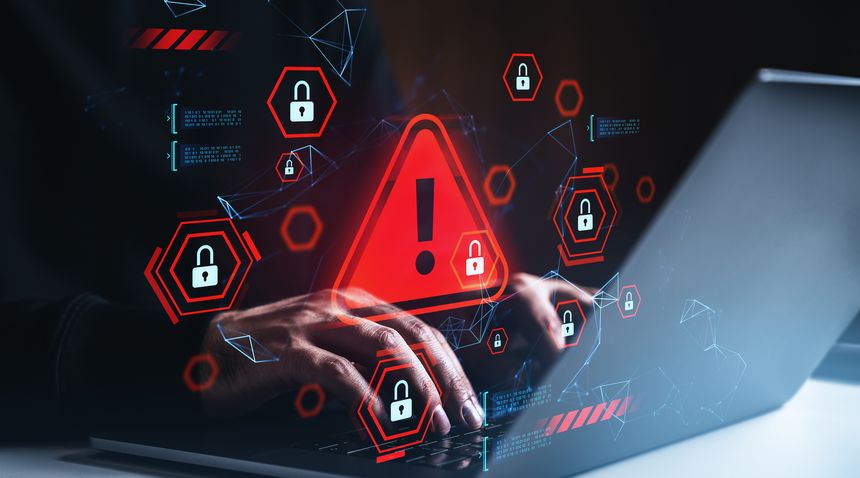 Hands typing on laptop with red warning triangle, digital padlock icons, and glowing tech graphics on dark background, concept of cybersecurity breach