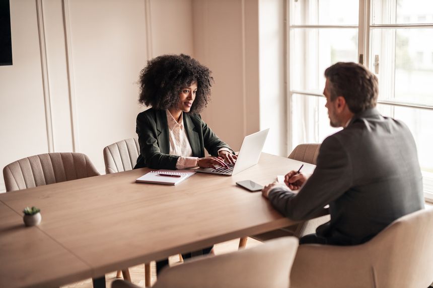 Two business colleagues engaging in a professional conversation during a business meeting at an office, promoting communication and teamwork within a professional environment.