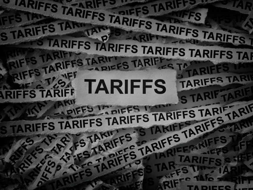 Strips of newspaper with the words Tariffs typed on them. Black and white.