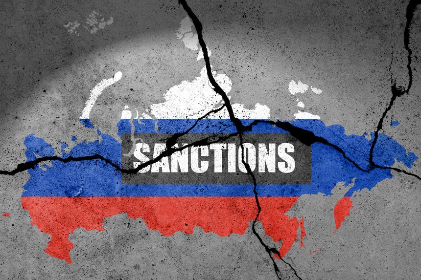 Flag map of Russia painted on a cracked wall with word SANCTIONS