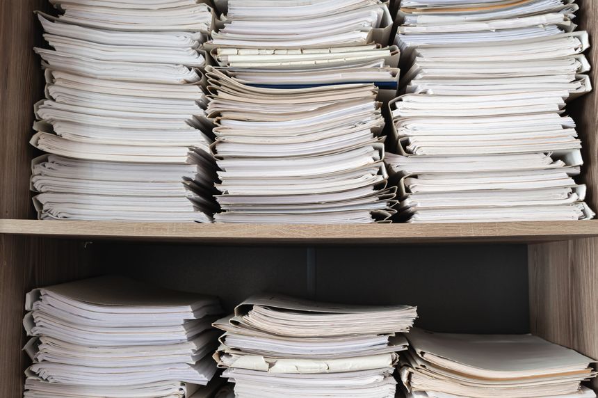 I organized various important documents on a shelf, showcasing archival and office supplies for easy access