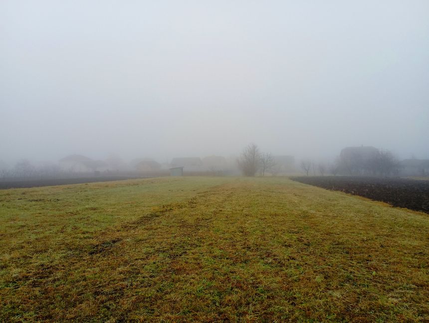 Autumn in the fields. from a fabulous autumn field, a view of the countryside with small houses shrouded in thick fog opens.
