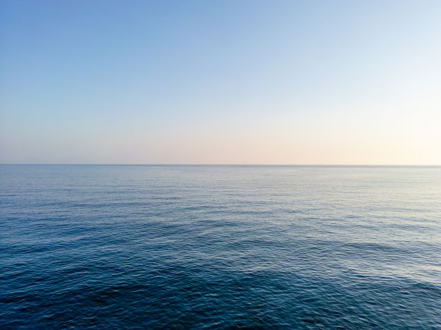 Aerial drone shot of the sea over the horizon, blue sea and clouds scenery