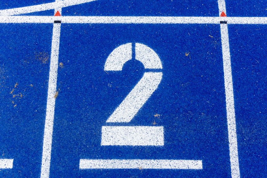 Lane number two is prominently displayed on a bright blue running track, highlighting the surface texture and athletic atmosphere of the stadium