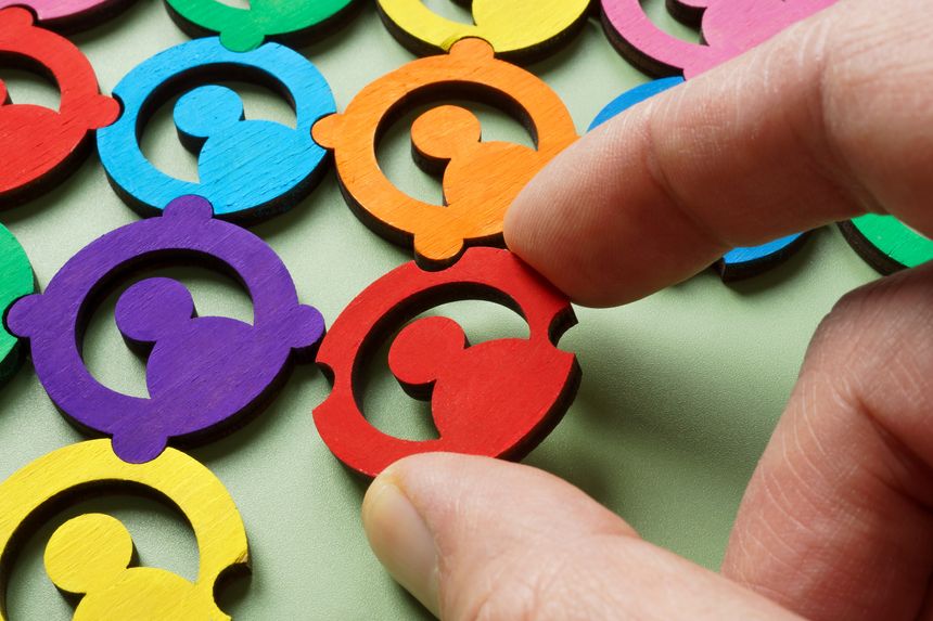 A hand adding a piece to a colorful puzzle. Diversity and team collaboration.